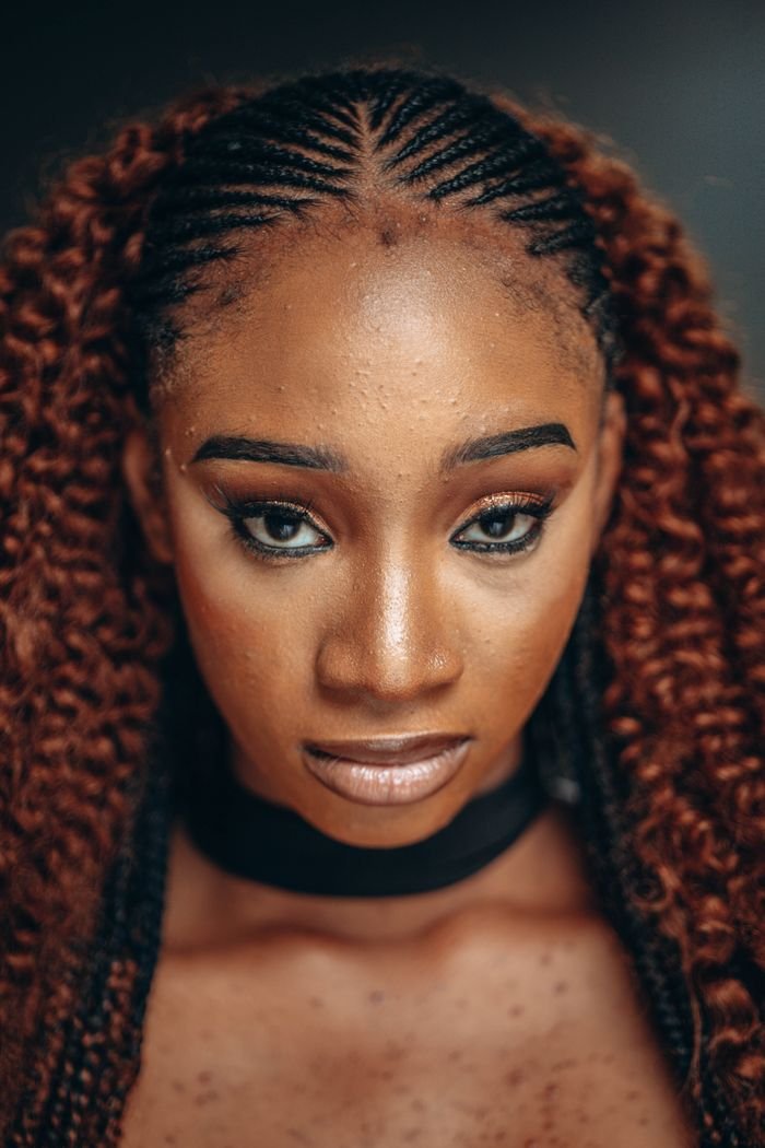 A striking close-up portrait of a woman with intricate braided hair and expressive eyes.