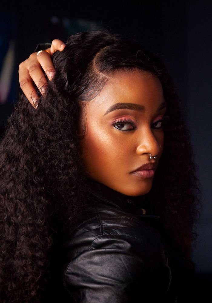 Portrait of a fashionable woman with curly hair and septum piercing, exuding confidence.